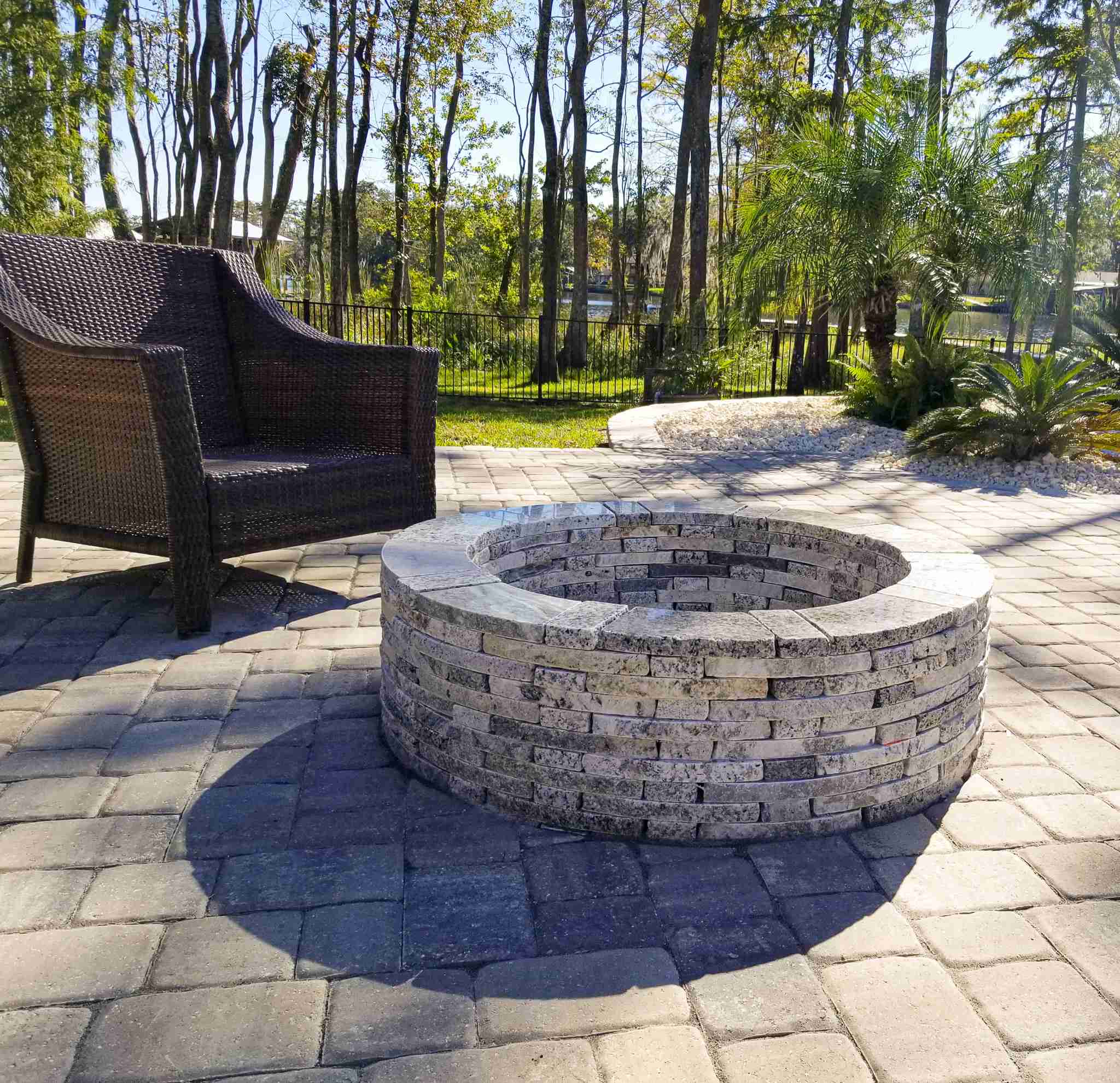 Waterfront patio with stone fire pit and wicker seating