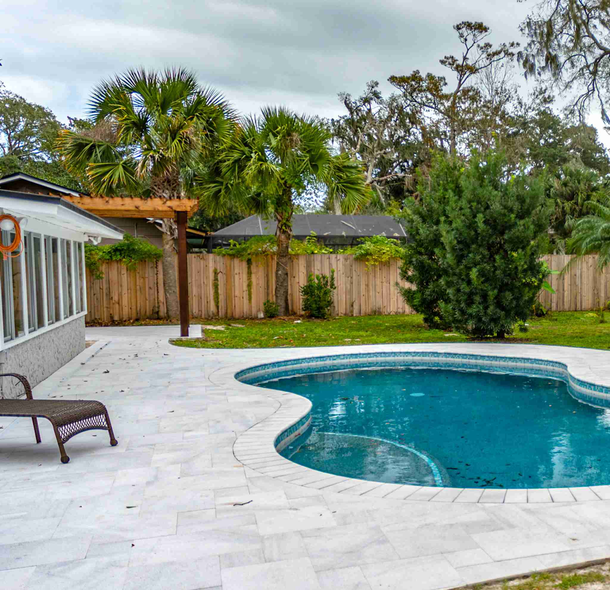 Paver pool deck with pergola and lounge chair