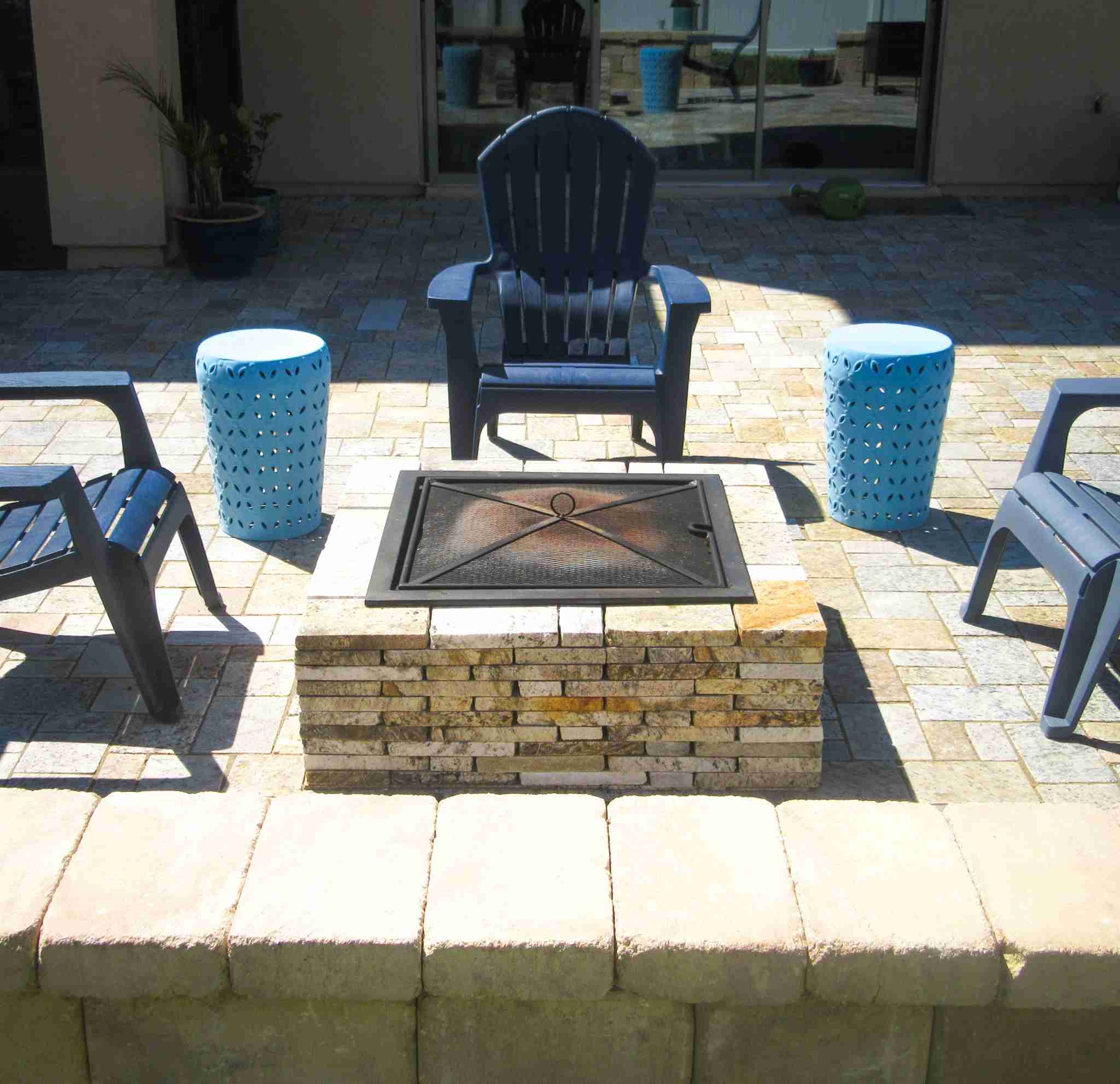 Square fire pit with paver seating wall and Adirondack chairs