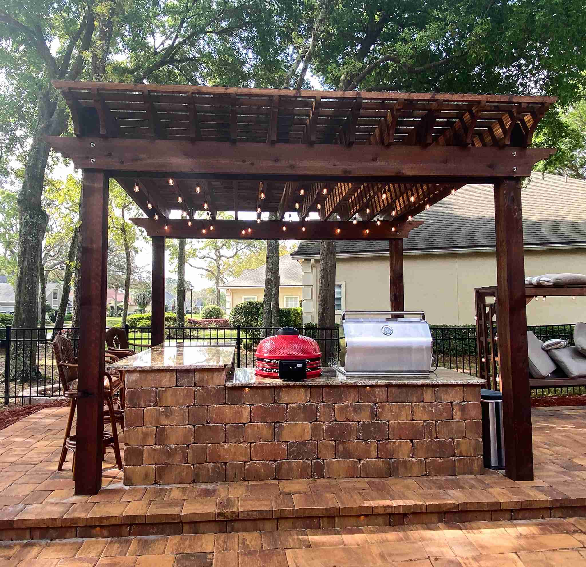 Pergola with outdoor kitchen bar and string lights at dusk