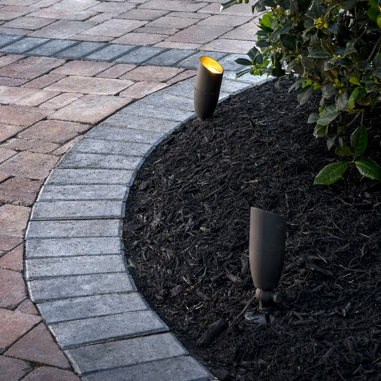 Landscape uplighting along paver walkway border